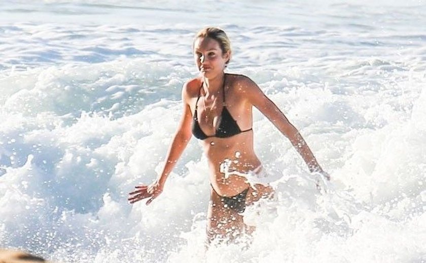 Candice Swanepoel brinca em praia brasileira em visita à família do marido