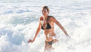 Candice Swanepoel brinca em praia brasileira em visita à família do marido