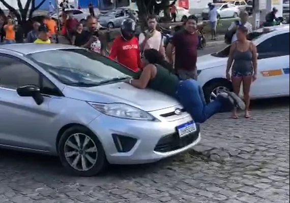 Mulher flagra companheiro com suposta amante e se joga em capô de veículo